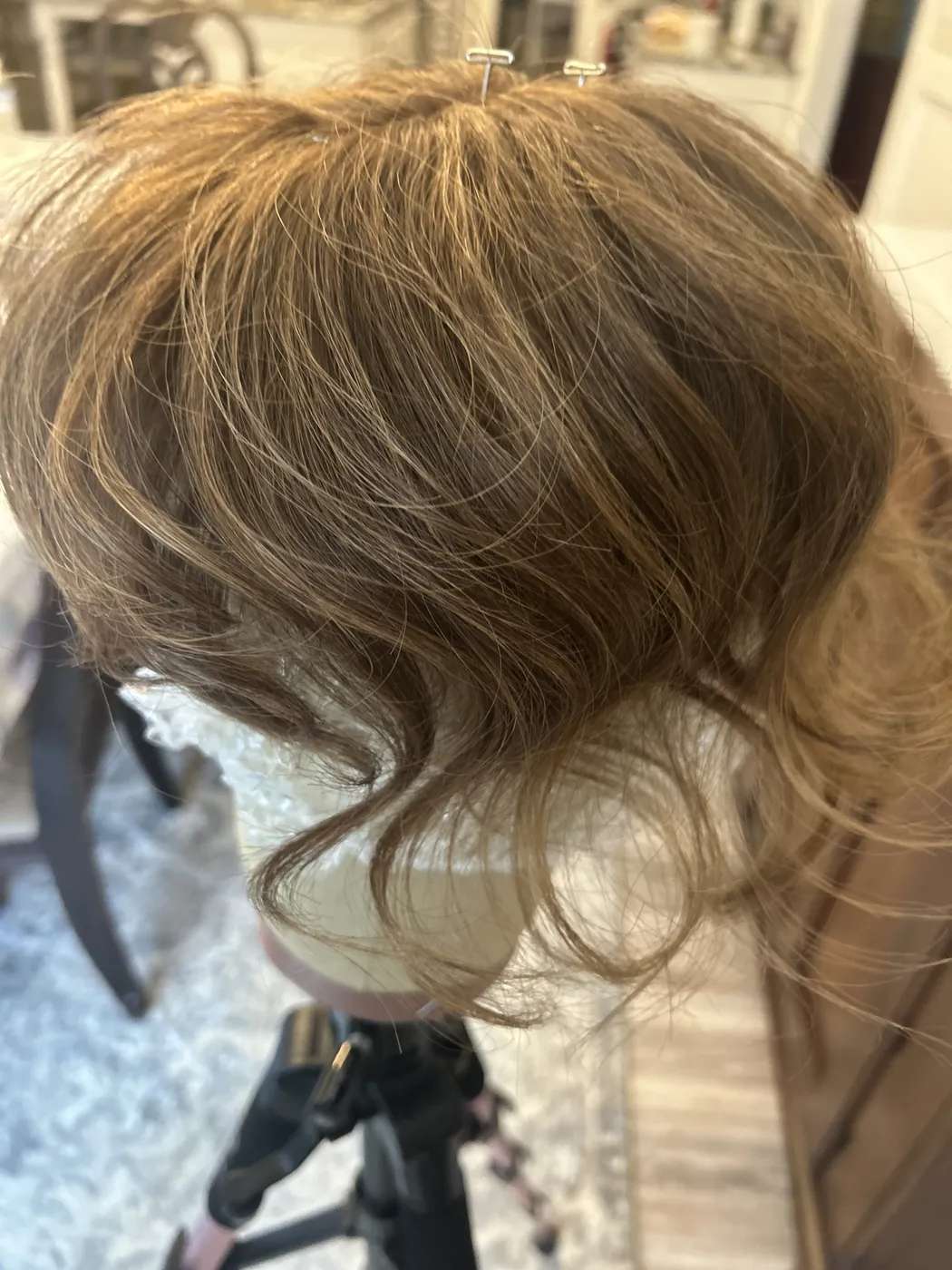 A custom-colored hair topper being built and blended on a block