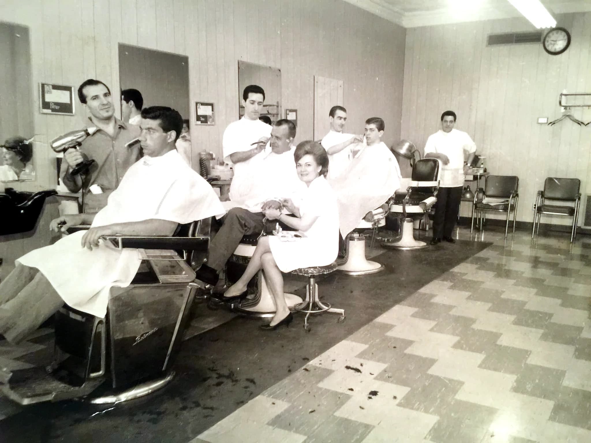 Madison Men's Barbershop in full swing — five barbers working, a manicurist mid-set, checkerboard floor